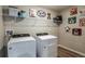 Functional laundry room with modern appliances, wire shelving, and quirky wall art at 14807 Summer Branch Dr, Lithia, FL 33547