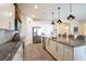 Bright kitchen features stainless steel appliances, white cabinets, large granite island, and stylish pendant lighting at 1512 Banner Elk St, Valrico, FL 33594