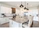 Bright kitchen with stainless steel appliances, white cabinets, large granite island, and stylish pendant lighting at 1512 Banner Elk St, Valrico, FL 33594