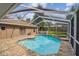 This screened-in pool and spa combo features a paver deck and is surrounded by lush landscaping at 160 Sage Cir, Crystal Beach, FL 34681