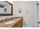 Bathroom vanity with granite countertop, sink, framed mirror, lighting, and silver faucet fixtures at 2421 Lake Point Ln, Clearwater, FL 33762