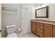 Bathroom featuring a toilet, towel rack, mirror, lighting, and vanity with granite counters and wood cabinets at 2421 Lake Point Ln, Clearwater, FL 33762