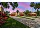 Beautiful sunset view of the home exterior featuring a patterned brick driveway and lush landscaping with palm trees at 2421 Lake Point Ln, Clearwater, FL 33762