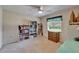Sunlit bedroom with a ceiling fan, filled bookshelves, and window with blinds overlooking trees at 2811 Barret Ave, Plant City, FL 33566