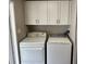 Functional laundry room with a washer, dryer, and overhead cabinets for convenient storage at 3041 Short Leaf St, Wesley Chapel, FL 33543