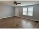 Bright living room features wood-look flooring, a ceiling fan, and large windows at 3041 Short Leaf St, Wesley Chapel, FL 33543