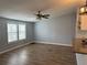 Bright living room features wood-look flooring, a ceiling fan, and large windows at 3041 Short Leaf St, Wesley Chapel, FL 33543