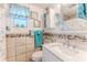 Nautical themed bathroom with custom shower curtain, decorative mirror, tiled walls, and single sink at 3181 Gulf Winds Cir, Hernando Beach, FL 34607