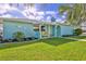 Exterior home view of manicured lawn, with palm trees and blue exterior at 3181 Gulf Winds Cir, Hernando Beach, FL 34607