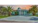 Charming waterfront home featuring a light-blue exterior, lush palm trees, and a spacious driveway at 3181 Gulf Winds Cir, Hernando Beach, FL 34607