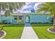 Charming blue home with a manicured lawn, palm trees, and inviting walkway at 3181 Gulf Winds Cir, Hernando Beach, FL 34607