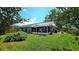 Spacious backyard with lush green grass, mature trees, and a screened patio at 3907 Orchard Hill Cir, Palm Harbor, FL 34684