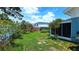 Large backyard featuring lush green grass, mature trees, and partial view of a screened in patio at 3907 Orchard Hill Cir, Palm Harbor, FL 34684