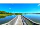 Picturesque view of a wooden dock extending into a serene lake with lush greenery surrounding the water at 3907 Orchard Hill Cir, Palm Harbor, FL 34684