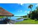 Scenic lake view from a charming gazebo surrounded by lush green vegetation and clear blue skies at 3907 Orchard Hill Cir, Palm Harbor, FL 34684