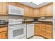 Bright kitchen with white appliances, wood cabinets, and a granite countertop at 4900 Brittany S Dr # 209, St Petersburg, FL 33715