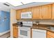 Charming kitchen featuring white appliances, wood cabinets, and blue accent wall at 4900 Brittany S Dr # 209, St Petersburg, FL 33715
