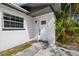 Home exterior featuring a white door with a small window and brick accents and lush landscaping at 5013 W Mccoy St, Tampa, FL 33616