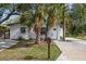 Charming white brick home featuring a manicured lawn and tropical landscaping at 5013 W Mccoy St, Tampa, FL 33616