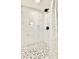 Modern shower with white marble and pebble tile accents at 5703 Andrea Dr, Holiday, FL 34690