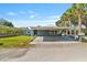 Single-story home featuring a convenient covered carport, manicured lawn and tropical trees at 6726 Udell Ln, Hudson, FL 34667