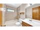 A well-lit bathroom features a tub with a shower, a sink with vanity, and a wooden door at 6915 N Hubert Ave, Tampa, FL 33614