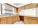 A kitchen featuring light wood cabinets, tile floors and a window with ornate ironwork at 6915 N Hubert Ave, Tampa, FL 33614