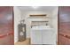 Functional laundry room with a washer, dryer, water heater and shelving for storage at 6915 N Hubert Ave, Tampa, FL 33614