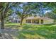 Exterior view of the home, showcasing the large screened-in lanai overlooking the lush green backyard and mature trees at 803 Woodcarver Ln, Brandon, FL 33510