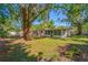 The backyard view of this home features mature trees, green grass and a screened in porch at 810 W River Dr, Temple Terrace, FL 33617