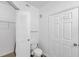 White bathroom featuring a toilet, louvered door, and a door leading to other rooms at 9602 Lake Chase Island Way # 9602, Tampa, FL 33626