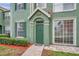 Well-maintained property entrance with green door, neat landscaping, and brick path at 9602 Lake Chase Island Way # 9602, Tampa, FL 33626