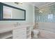 Bathroom features marble vanity, large mirror, toilet and combined bathtub and shower behind a glass enclosure at 100 Sands Point Dr, Tierra Verde, FL 33715