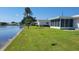 A serene backyard featuring a pond, lush green lawn, and clear blue skies at 10040 38Th N Way, Pinellas Park, FL 33782