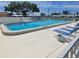 A sparkling outdoor pool with lounge chairs is surrounded by a white fence and lush landscaping at 10040 38Th N Way, Pinellas Park, FL 33782