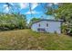 Spacious backyard with a well-maintained lawn, partial view of the blue home, and lush landscaping at 10208 N 23Rd St, Tampa, FL 33612