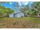 Backyard with the back of the blue house, grass, trees, and wooden fencing at 10208 N 23Rd St, Tampa, FL 33612