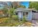 Charming home exterior featuring a white door, trees, and vibrant greenery at 10208 N 23Rd St, Tampa, FL 33612