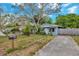 View of a blue house with a well kept lawn, mailbox, driveway, and mature trees at 10208 N 23Rd St, Tampa, FL 33612