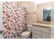 A toilet sits beside the vanity with granite countertops and a floral patterned shower curtain at 10313 Wine Press Ave, Riverview, FL 33578