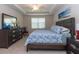 Well-lit bedroom with a tray ceiling, large dresser, and cozy bed with a tranquil beach-themed decor at 10313 Wine Press Ave, Riverview, FL 33578