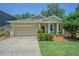 Charming single-story home featuring manicured lawn, mature trees, and inviting beige facade with a two car garage at 12212 Mcmullen Loop, Riverview, FL 33569