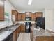 Well-equipped kitchen with stone countertops, brown cabinetry, and modern appliances at 12212 Mcmullen Loop, Riverview, FL 33569