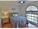 Cozy bedroom featuring a ceiling fan, wood-look floors, and a large arched window with natural light at 12501 Palomino Ct, Tampa, FL 33626