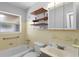 Bright bathroom featuring yellow tile, updated vanity, wooden shelving, and a bathtub-shower combination at 133 43Rd Ne Ave, St Petersburg, FL 33703