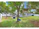 Spacious backyard with lush green lawn, mature trees, play set, and screened porch perfect for outdoor fun at 13404 Fladgate Mark Dr, Riverview, FL 33579