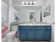 Updated bathroom with blue vanity, dual sinks, granite countertops, large mirror, and fun shower curtain at 13404 Fladgate Mark Dr, Riverview, FL 33579
