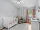 Light-filled Bedroom with white crib, glider chair, and window with pink curtains on hardwood floor at 13404 Fladgate Mark Dr, Riverview, FL 33579