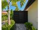 Modern horizontal backyard gate with stone pavers, surrounded by tropical landscaping at 13916 Wellesford Way, Tampa, FL 33624