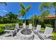 Outdoor fire pit area with chairs surrounded by lush landscaping and beautiful palm trees at 13916 Wellesford Way, Tampa, FL 33624